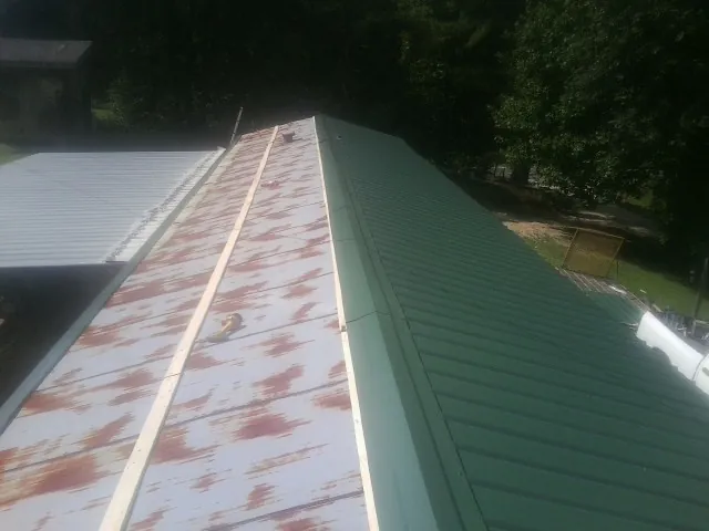 Old rusted panels beside newly installed green metal roofing — Wind Damage Roof Repair by Roofing Brothers in Nescopeck