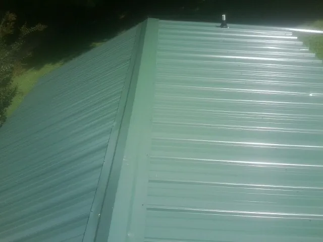 New green metal panels meeting at the ridge of a roof — Flat Roof Repair work by our crew in Nescopeck
