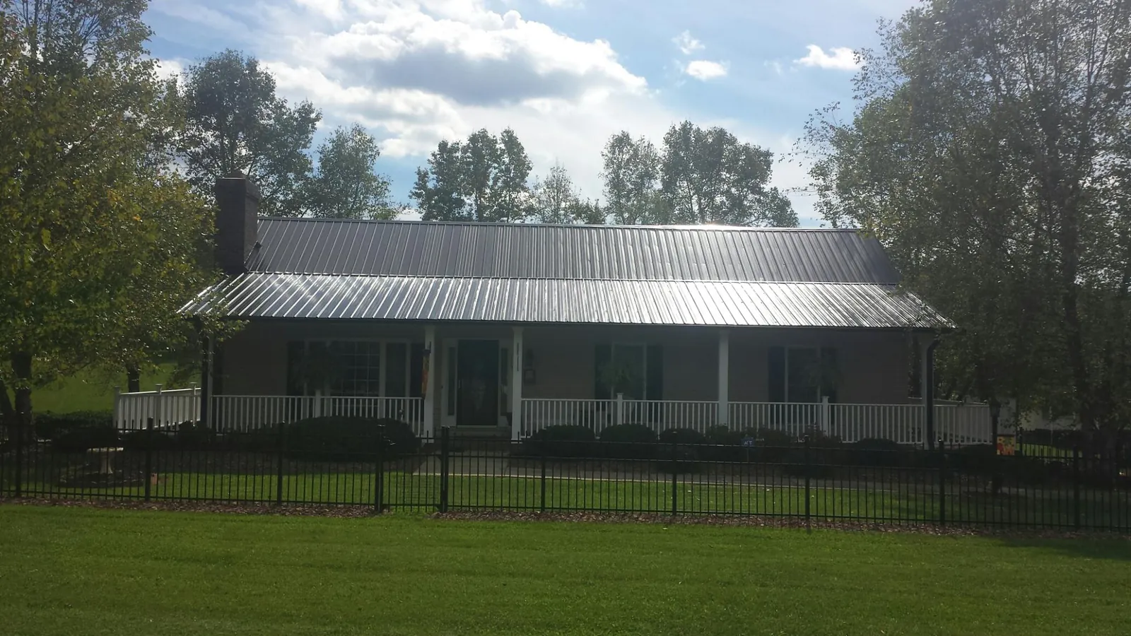 Gray metal roof on a brick ranch with a full width front porch — Gutter Guard Installation work by our crew in Nescopeck