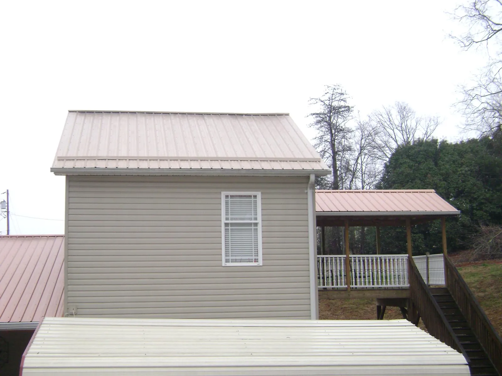 Tan metal roofs on a two story addition and attached porch, from a Roof Replacement job in Nescopeck