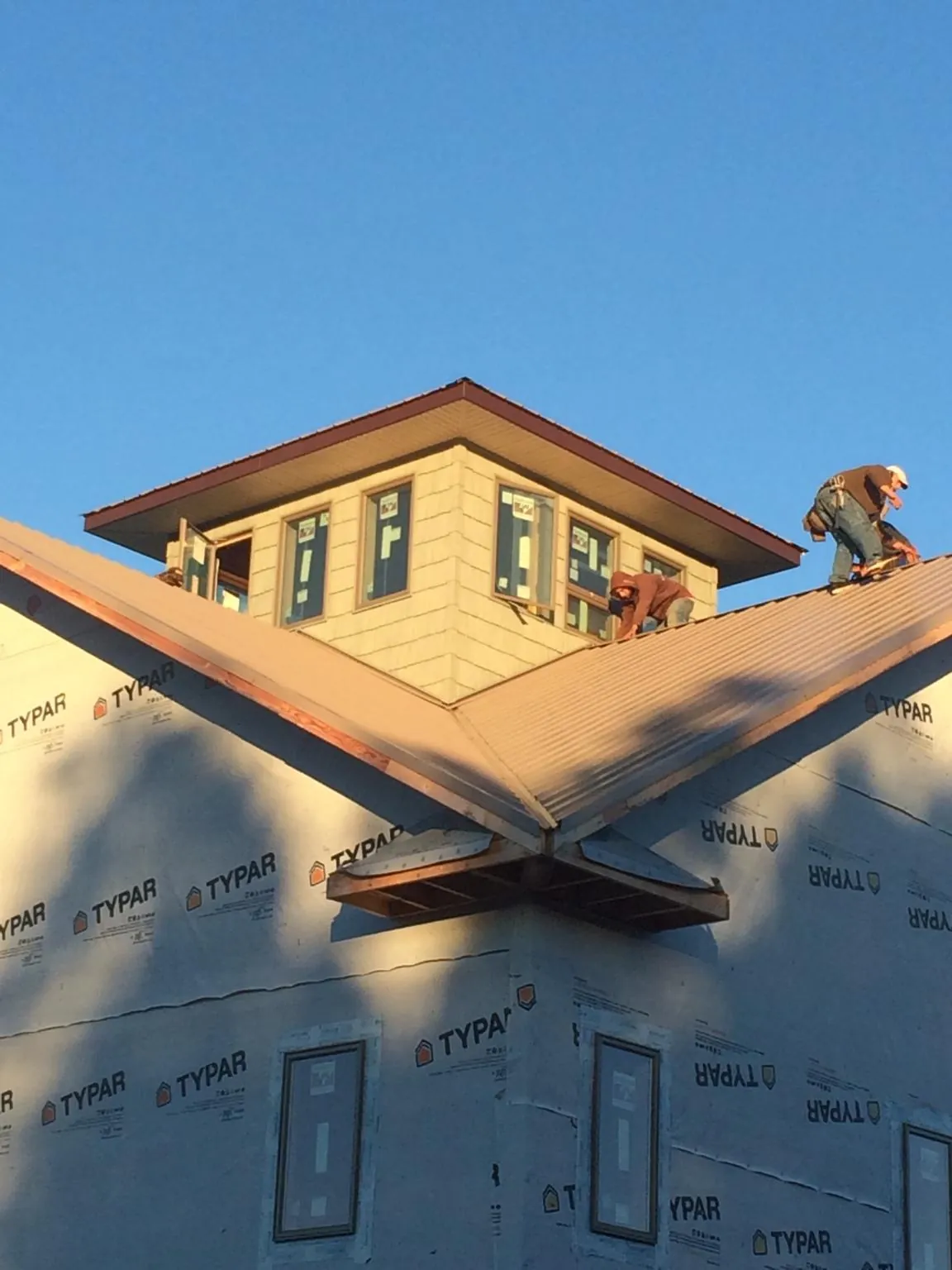 Roofers working around a rooftop cupola on a new metal roof at sunset — Roof Waterproofing in Nescopeck by Roofing Brothers